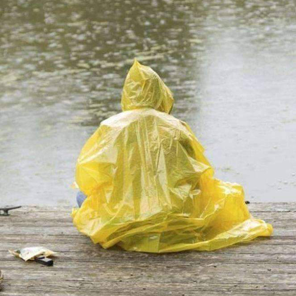 sitting on a dock in the rain wearing yellow poncho